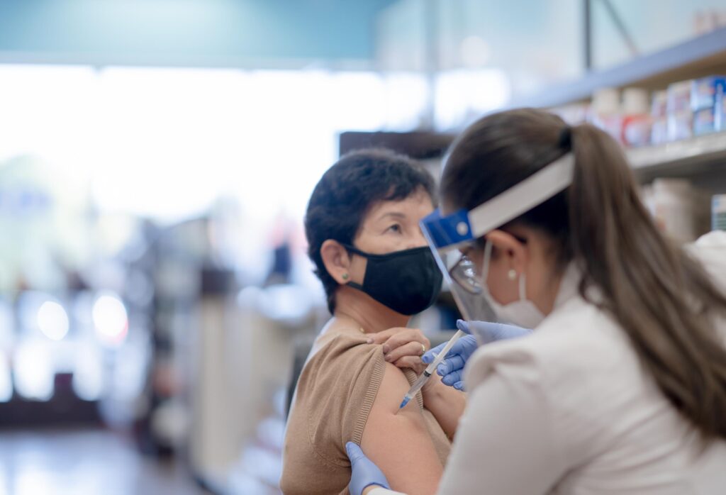 A senior woman of Asian descent is receiving her COVID-19 vaccine injection at the pharmacy.